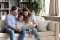 Uma família sentada confortavelmente num sofá e a olhar para um tablet em conjunto.