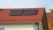 A imagem mostra o telhado de uma casa vermelha na qual foi montado um coletor solar térmico.