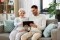 A imagem mostra uma mulher idosa e um jovem num sofá, olhando juntos para um tablet, como símbolo da facilidade de pesquisa com o localizador de produtos Viessmann.