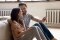 Um casal feliz senta-se em frente a um sistema de aquecimento e segura um smartphone.