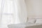 A imagem mostra um quarto com uma janela aberta e cortinados que se abrem.